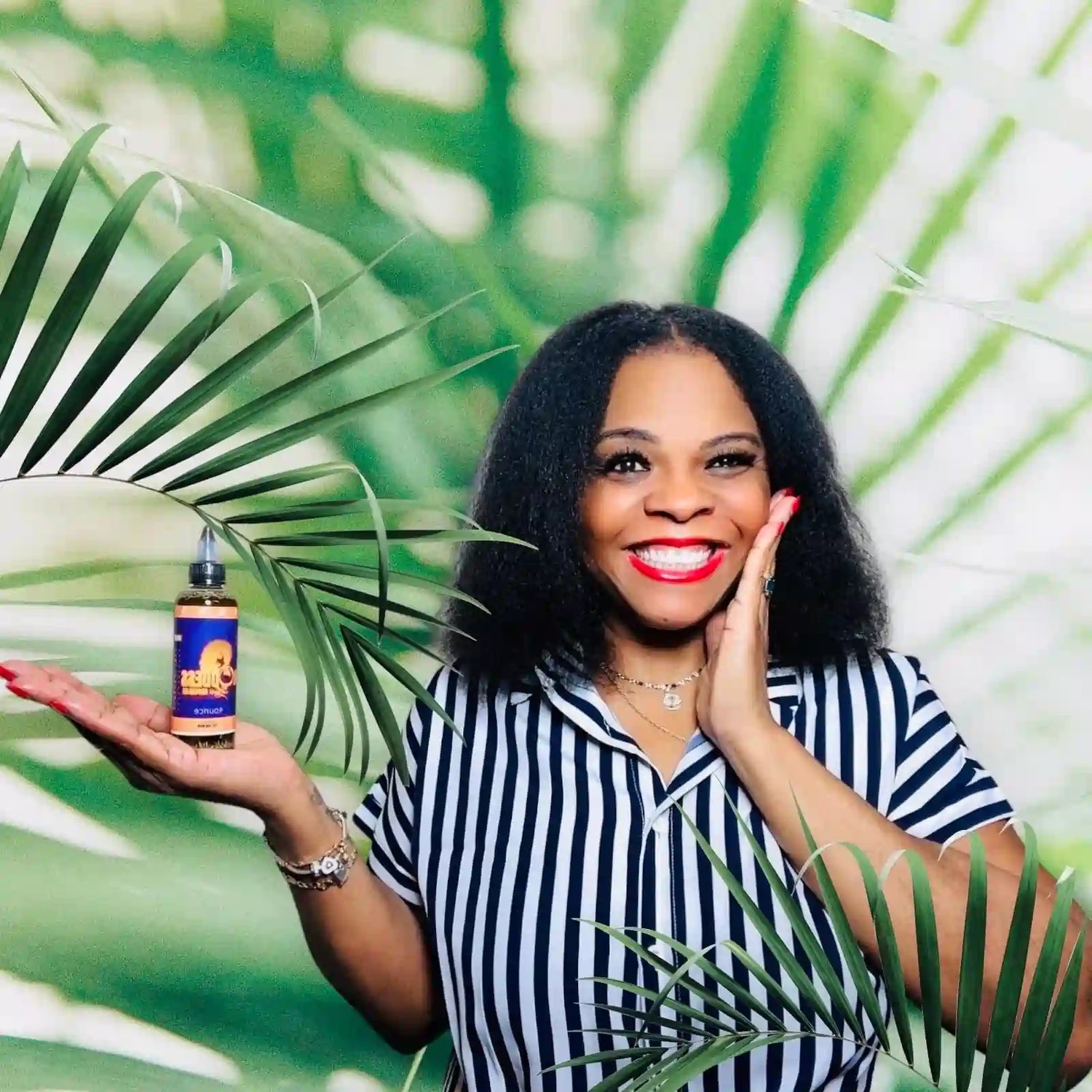 Woman holding a bottle of hair product with green leaves in the background